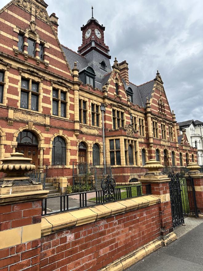 The red-brick and terracotta facade of Victoria Baths, with its clock tower and 'Males 1st Class' entrance lettering